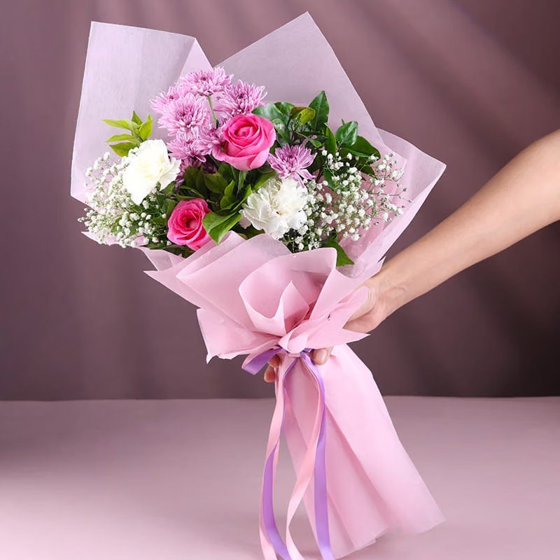 pink and white flower bouquet with roses carnations and daisy in pink wrapping